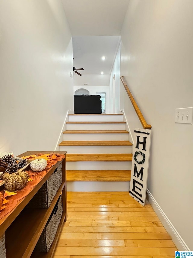 stairs featuring wood-type flooring and ceiling fan