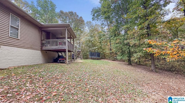 view of yard featuring a trampoline and a deck