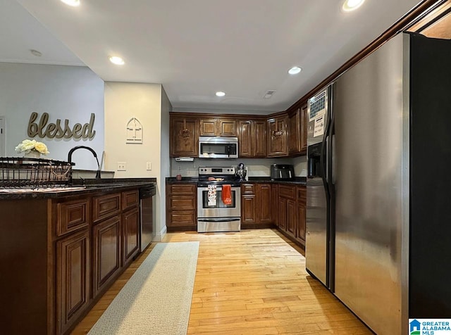 kitchen with appliances with stainless steel finishes, dark brown cabinetry, sink, and light wood-type flooring