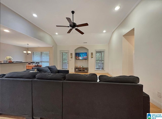 living room with vaulted ceiling, wood-type flooring, and ceiling fan with notable chandelier