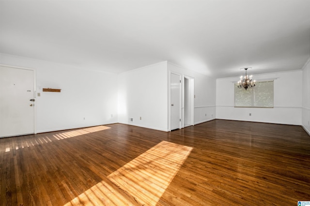 unfurnished living room with an inviting chandelier and dark hardwood / wood-style flooring