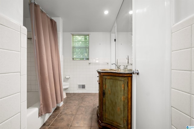 full bathroom with toilet, tile patterned flooring, shower / tub combo, vanity, and tile walls