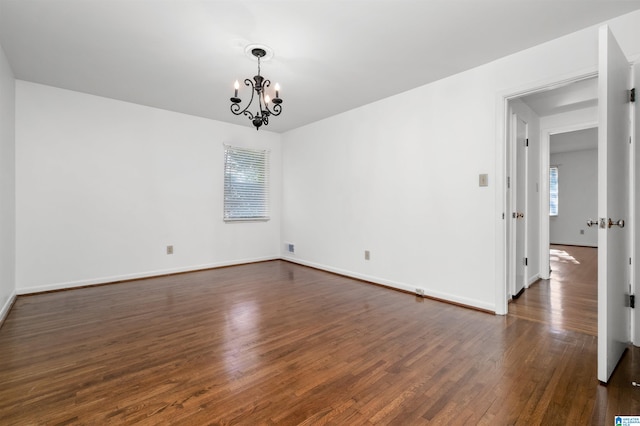 unfurnished room with dark wood-type flooring and an inviting chandelier