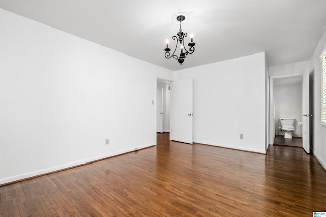 unfurnished room featuring dark wood-type flooring and an inviting chandelier