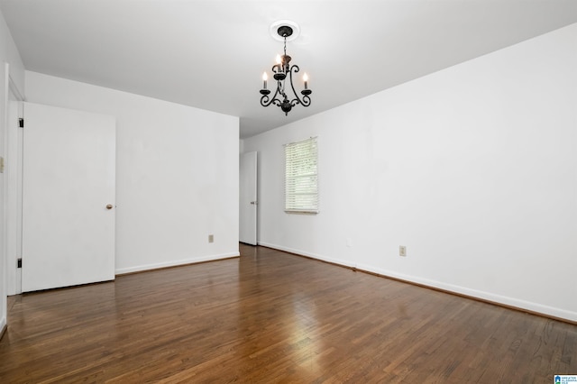 unfurnished room featuring an inviting chandelier and dark hardwood / wood-style floors