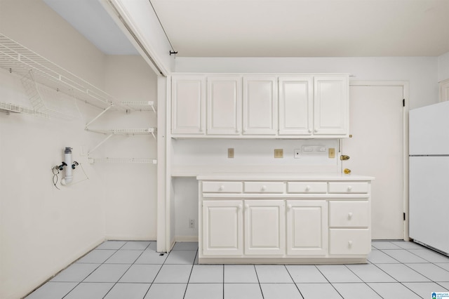 kitchen with white cabinetry, light tile patterned floors, and white refrigerator