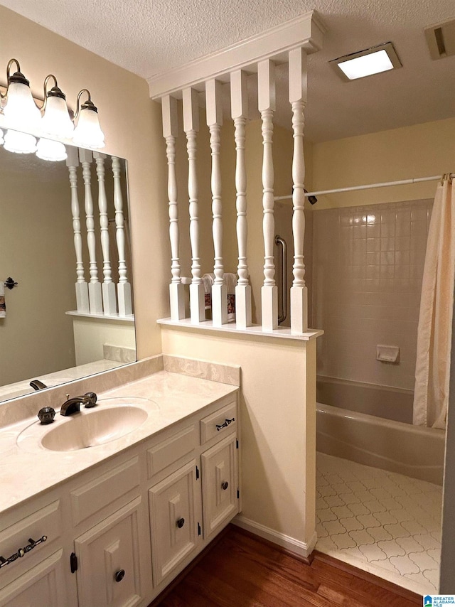 bathroom with vanity, a textured ceiling, wood-type flooring, and shower / tub combo