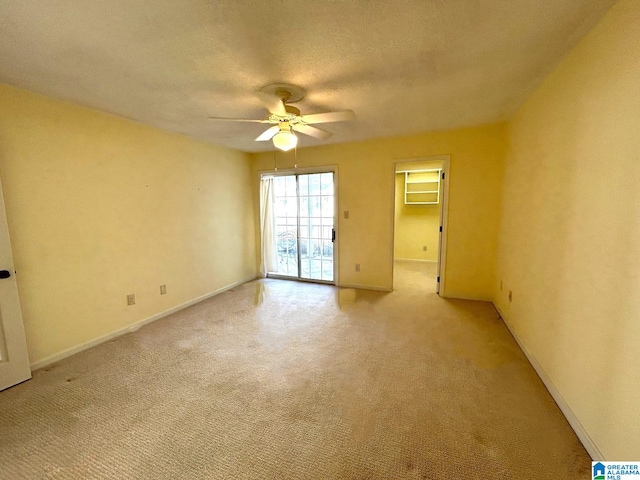 unfurnished room featuring ceiling fan, light carpet, and a textured ceiling