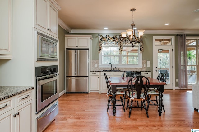 dining space with light wood-type flooring, a chandelier, sink, and plenty of natural light