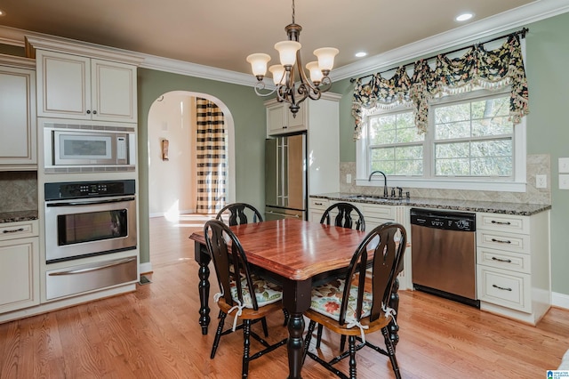 dining room with ornamental molding, sink, a notable chandelier, and light hardwood / wood-style floors