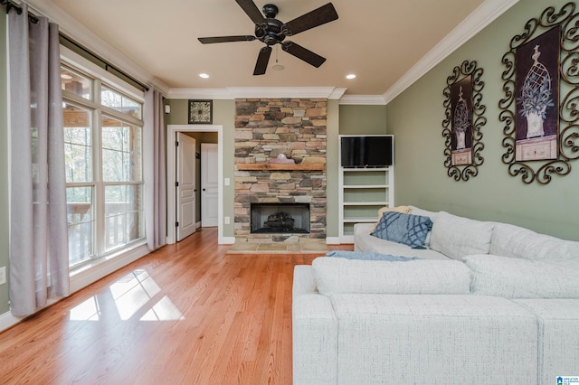 living room featuring a fireplace, ceiling fan, light hardwood / wood-style flooring, and ornamental molding