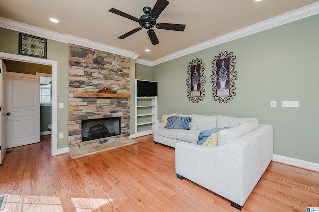 living room featuring a stone fireplace, hardwood / wood-style floors, ceiling fan, and crown molding