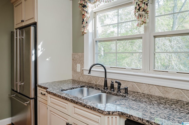 kitchen with high quality fridge, a healthy amount of sunlight, sink, and cream cabinetry