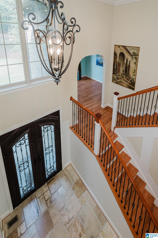 foyer featuring french doors, a notable chandelier, and crown molding