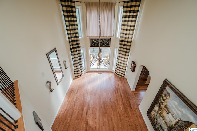 interior space with a towering ceiling, hardwood / wood-style flooring, and an inviting chandelier