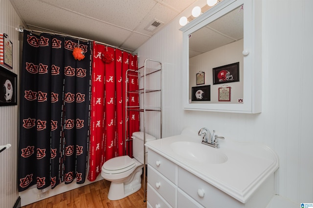 bathroom featuring wood-type flooring, vanity, a shower with shower curtain, toilet, and a drop ceiling