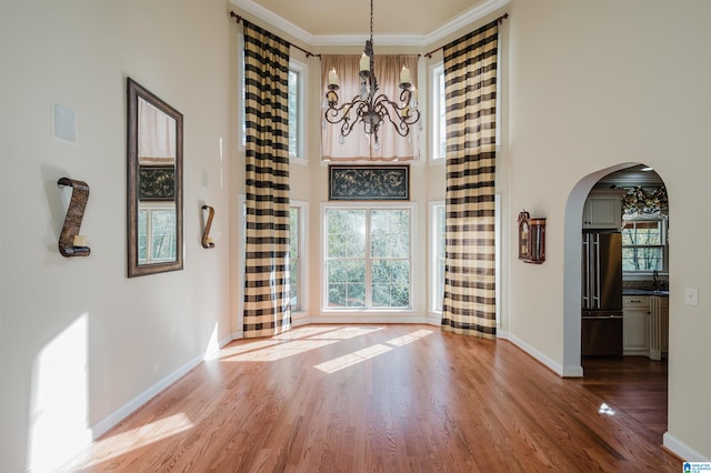 interior space with a high ceiling, a wealth of natural light, wood-type flooring, and crown molding