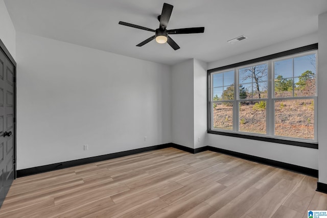 empty room with light wood-style flooring, visible vents, ceiling fan, and baseboards