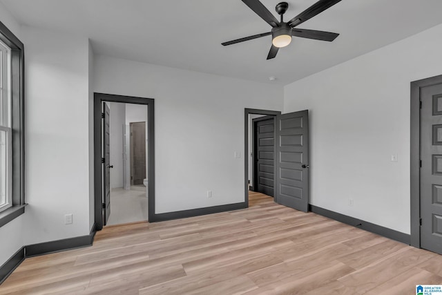 unfurnished bedroom with ensuite bath, light wood-style flooring, and baseboards