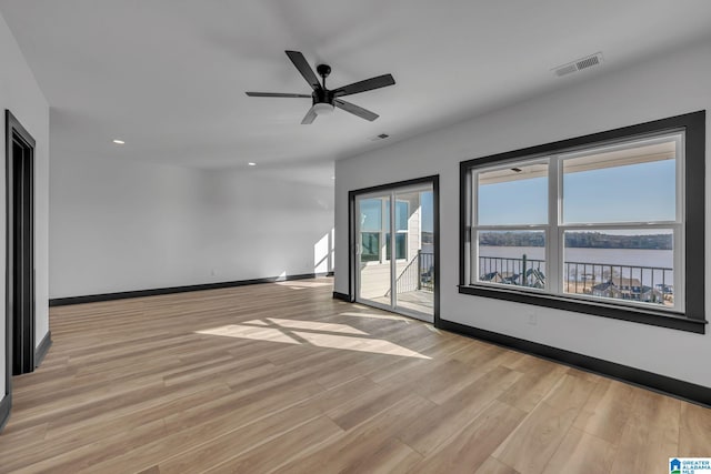 spare room with baseboards, a water view, visible vents, and light wood-style floors