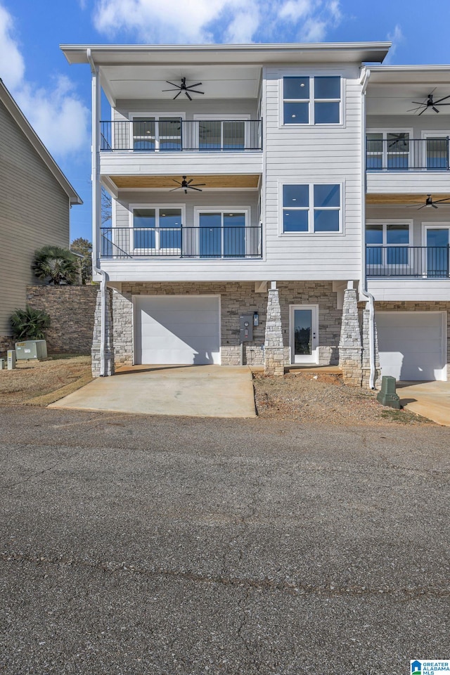 view of front of property featuring a garage, driveway, ceiling fan, and a balcony