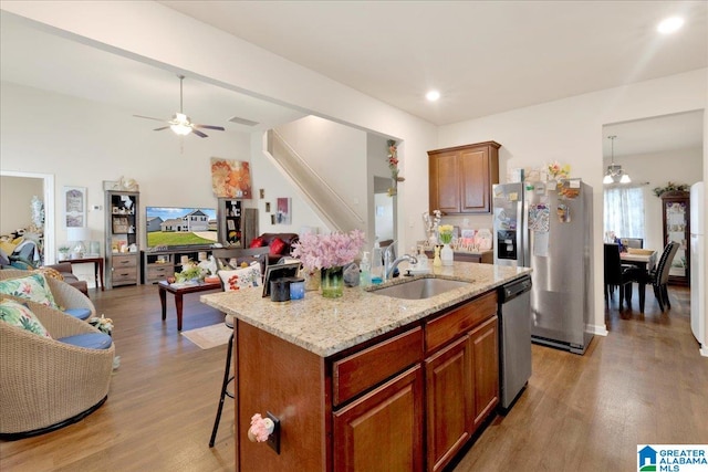 kitchen with appliances with stainless steel finishes, light hardwood / wood-style flooring, a breakfast bar area, and an island with sink