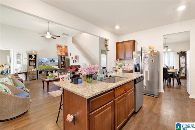 kitchen with sink, dark wood-type flooring, stainless steel appliances, a kitchen breakfast bar, and an island with sink