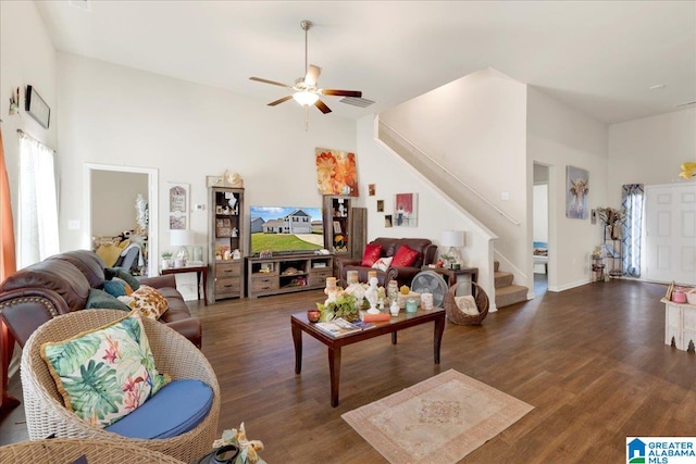 living room with ceiling fan, a towering ceiling, and dark wood-type flooring