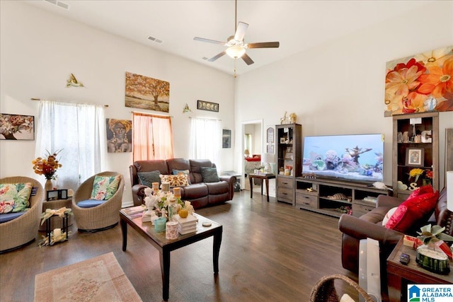 living room featuring a towering ceiling, dark hardwood / wood-style flooring, and ceiling fan