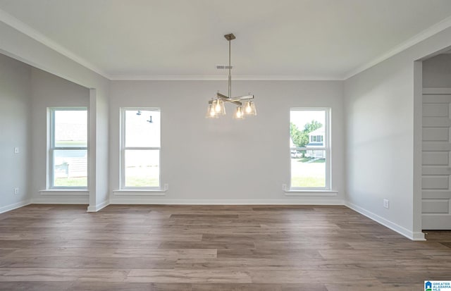 unfurnished room featuring hardwood / wood-style flooring, a notable chandelier, a healthy amount of sunlight, and ornamental molding