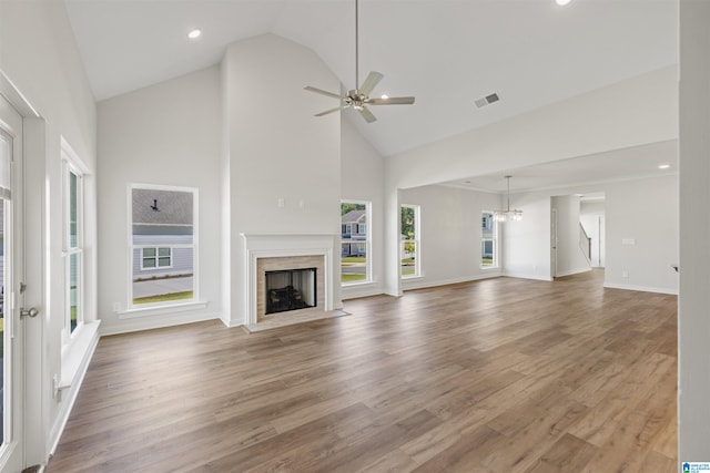 unfurnished living room with ceiling fan with notable chandelier, hardwood / wood-style flooring, and high vaulted ceiling