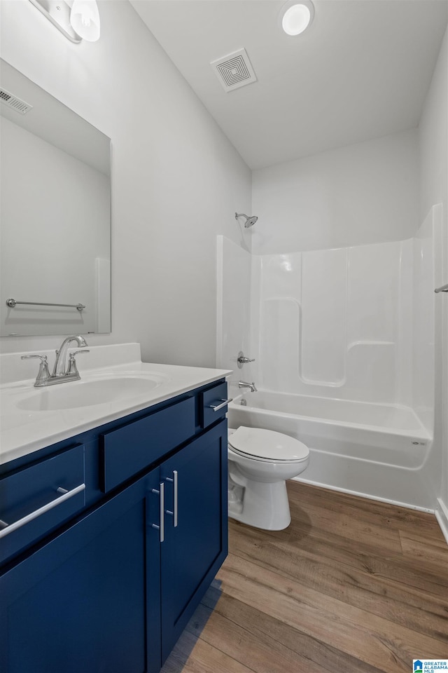 full bathroom featuring toilet, hardwood / wood-style flooring, shower / washtub combination, and vanity