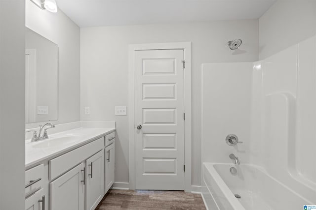 bathroom with hardwood / wood-style flooring, shower / bath combination, and vanity