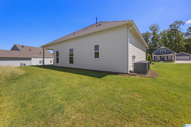 back of house with central air condition unit and a yard