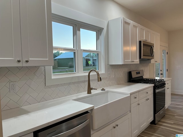 kitchen featuring appliances with stainless steel finishes, decorative backsplash, sink, and white cabinetry