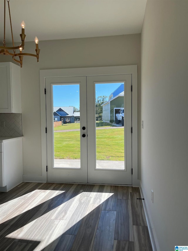 doorway to outside with an inviting chandelier, dark wood-type flooring, and french doors