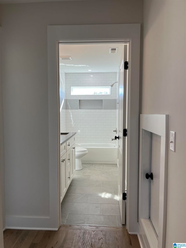 full bathroom featuring vanity, toilet, tiled shower / bath combo, and hardwood / wood-style floors