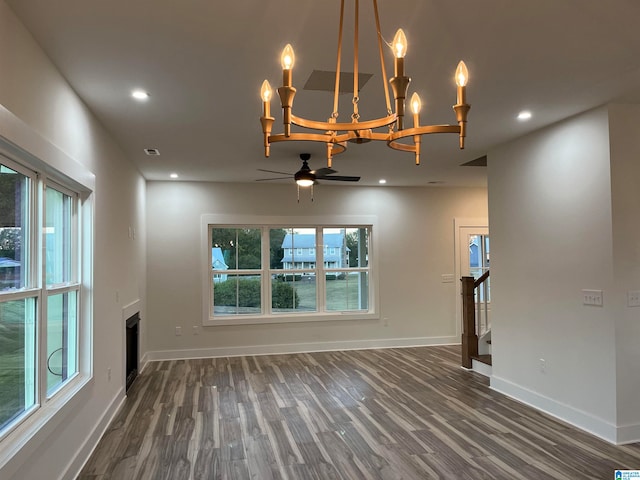 unfurnished living room with ceiling fan with notable chandelier and dark hardwood / wood-style flooring