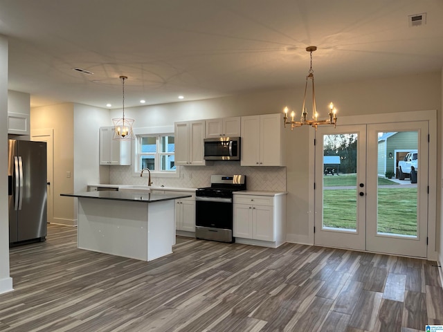 kitchen with a wealth of natural light, white cabinets, decorative light fixtures, and stainless steel appliances