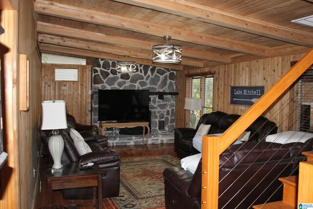 living room featuring beam ceiling, hardwood / wood-style flooring, wooden ceiling, a stone fireplace, and wooden walls