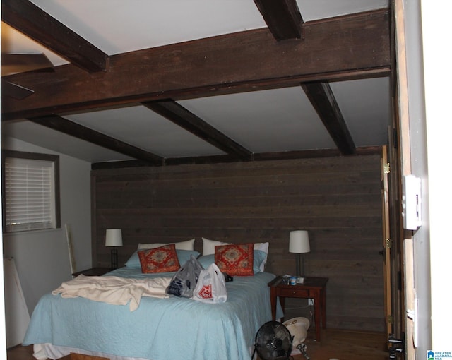 bedroom featuring hardwood / wood-style floors, beam ceiling, wooden walls, and ceiling fan