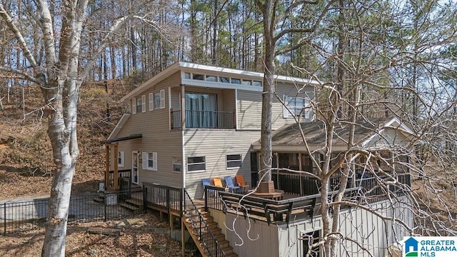 rear view of property with fence and stairway