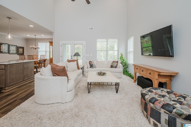 living room with ceiling fan with notable chandelier, a towering ceiling, ornamental molding, and dark hardwood / wood-style floors