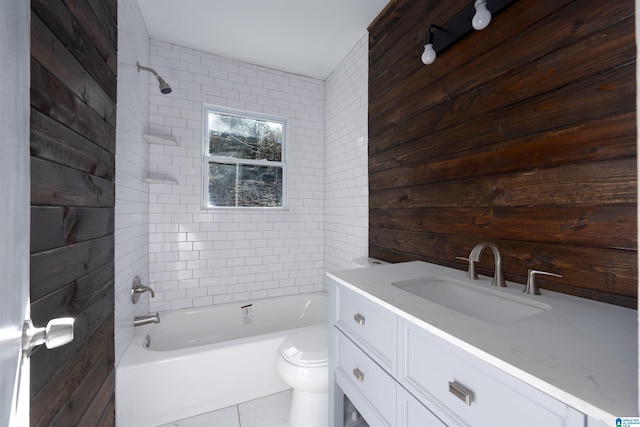 full bathroom with toilet, vanity, tiled shower / bath combo, wooden walls, and tile patterned floors