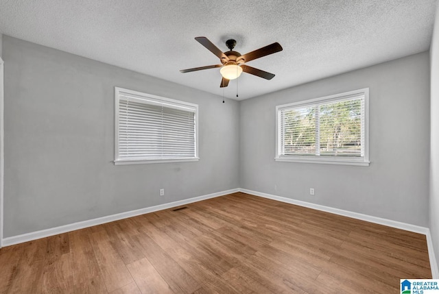 unfurnished room with ceiling fan, hardwood / wood-style floors, and a textured ceiling