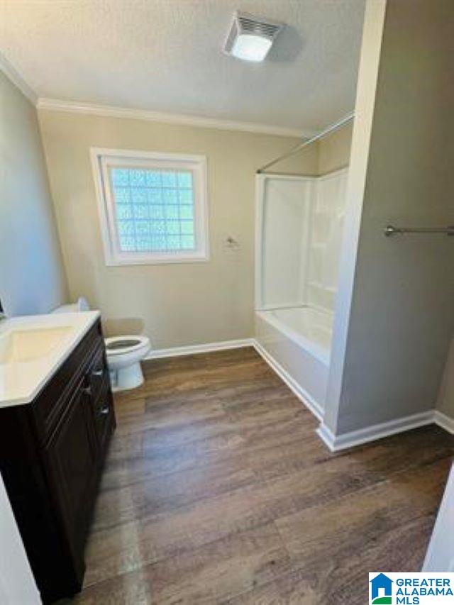 full bathroom with hardwood / wood-style floors, toilet, vanity, crown molding, and shower / bathtub combination