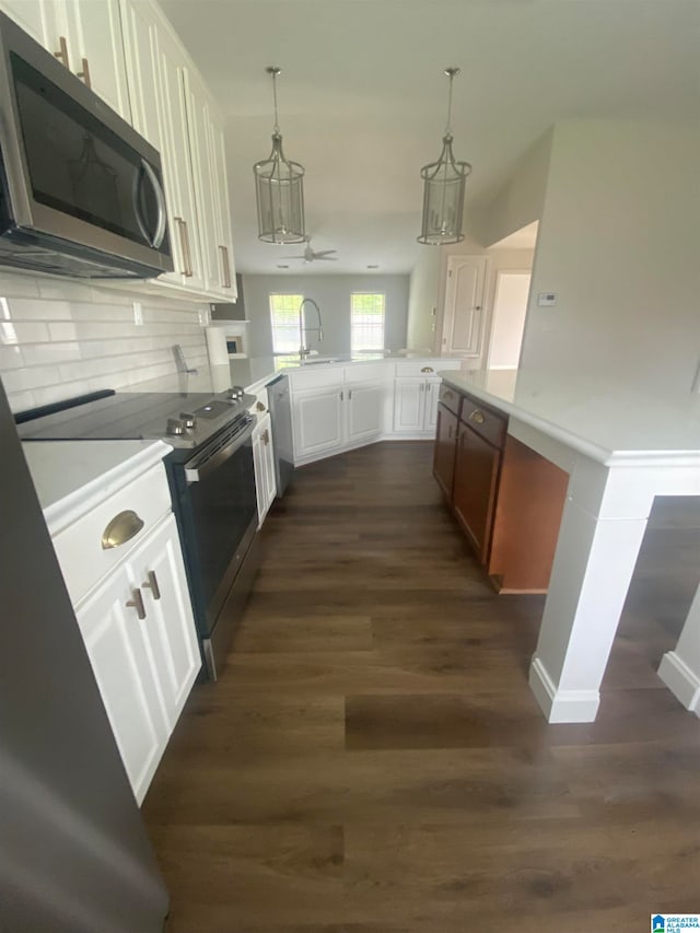 kitchen with white cabinets, stainless steel appliances, dark wood-type flooring, and pendant lighting