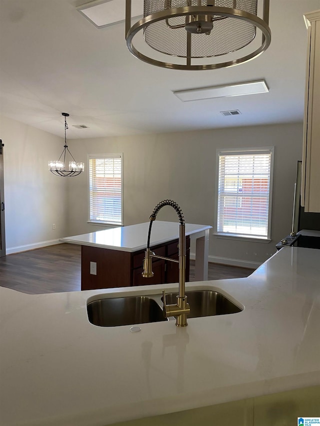 kitchen featuring sink, a center island, decorative light fixtures, dark wood-type flooring, and a chandelier