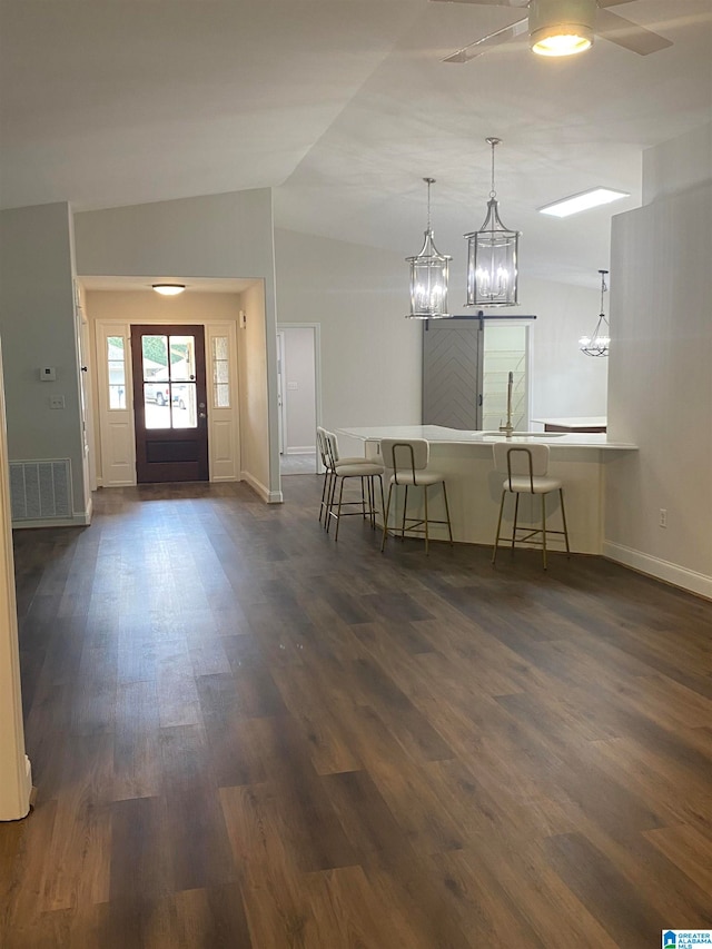 entryway featuring lofted ceiling, dark hardwood / wood-style flooring, and ceiling fan with notable chandelier