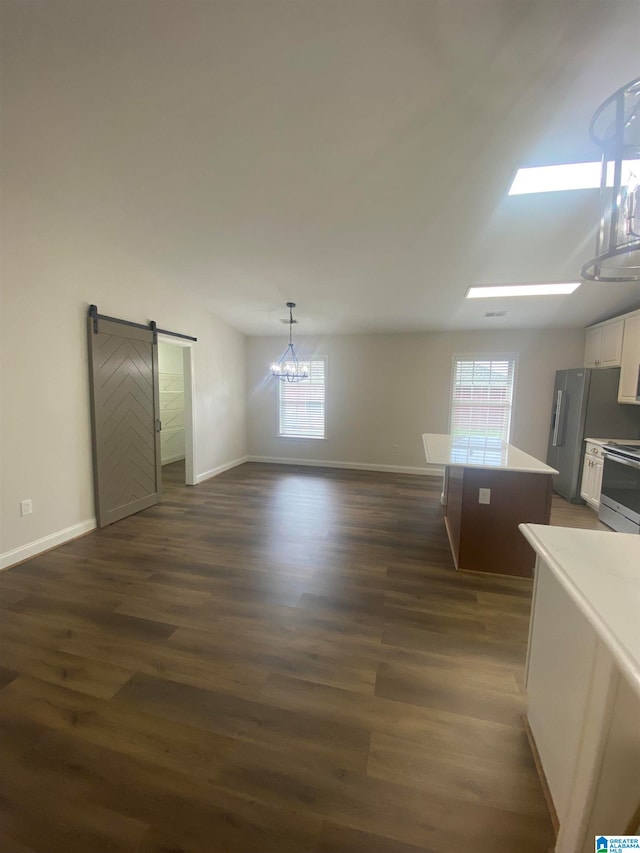 interior space with a wealth of natural light, dark wood-type flooring, and a barn door